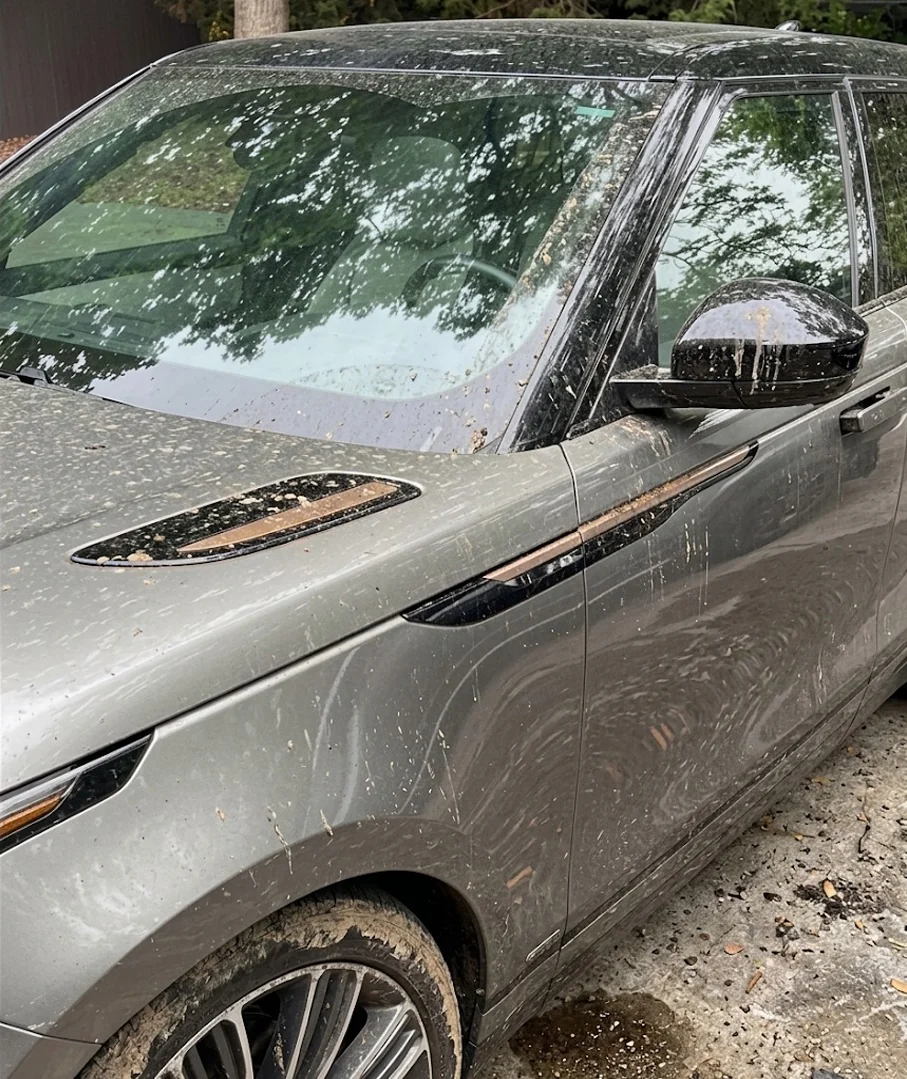 The same Range Rover Velar before the wash, covered in mud splatter and debris.